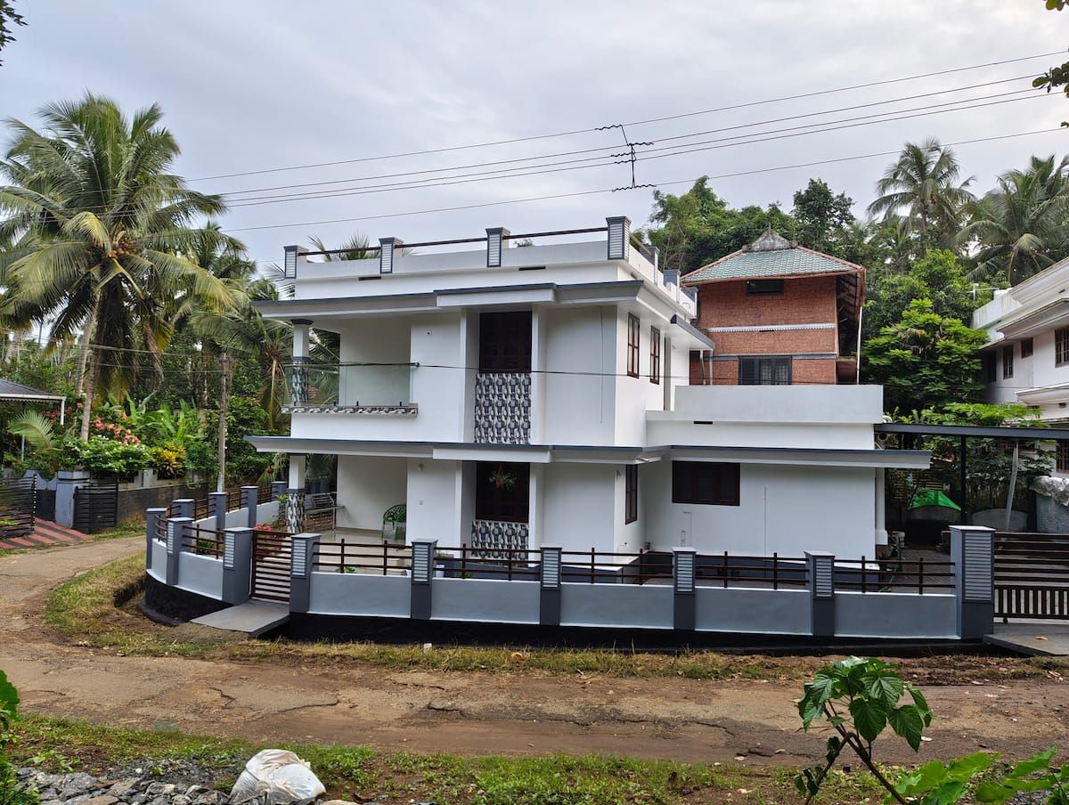 White two-storey Future Homes Homestay house behind a grey compound wall at the corner lane.