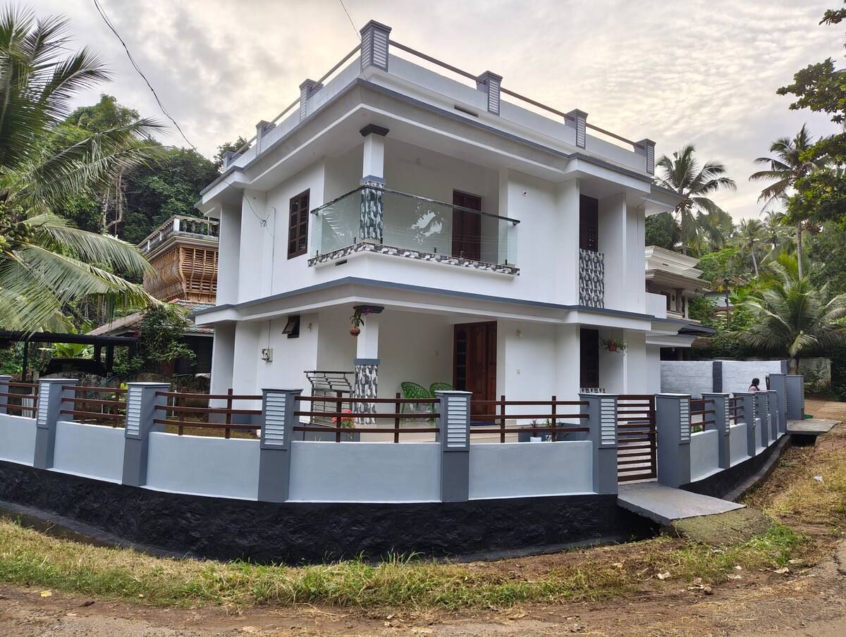 Front of the white two-storey house with balcony and gate.