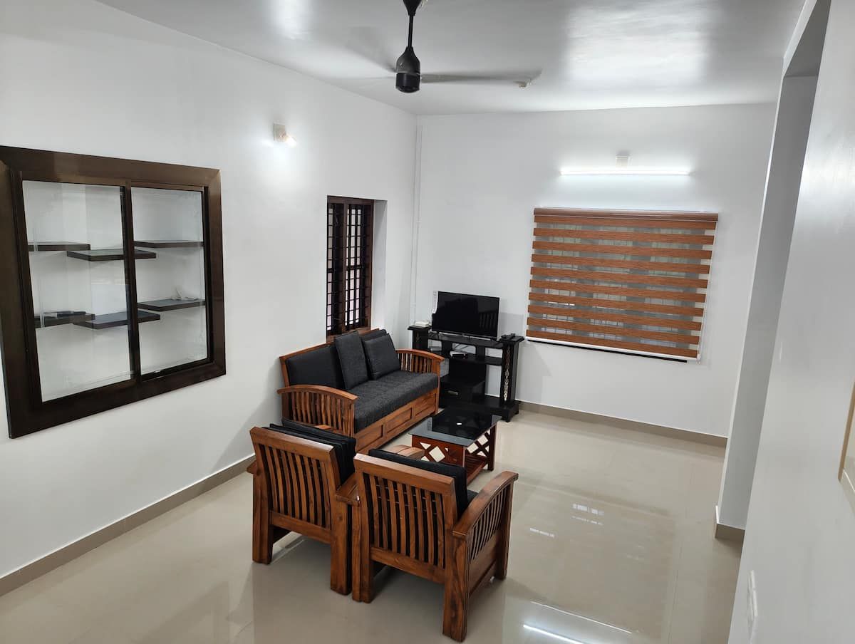 Living room with wooden seating, TV unit and window blind.