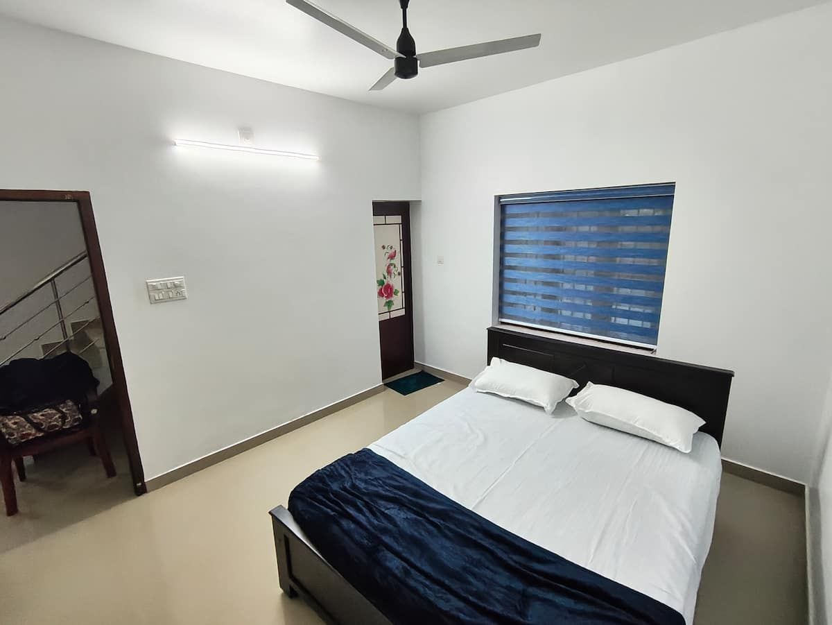 Second master bedroom with king bed and blue window blind.
