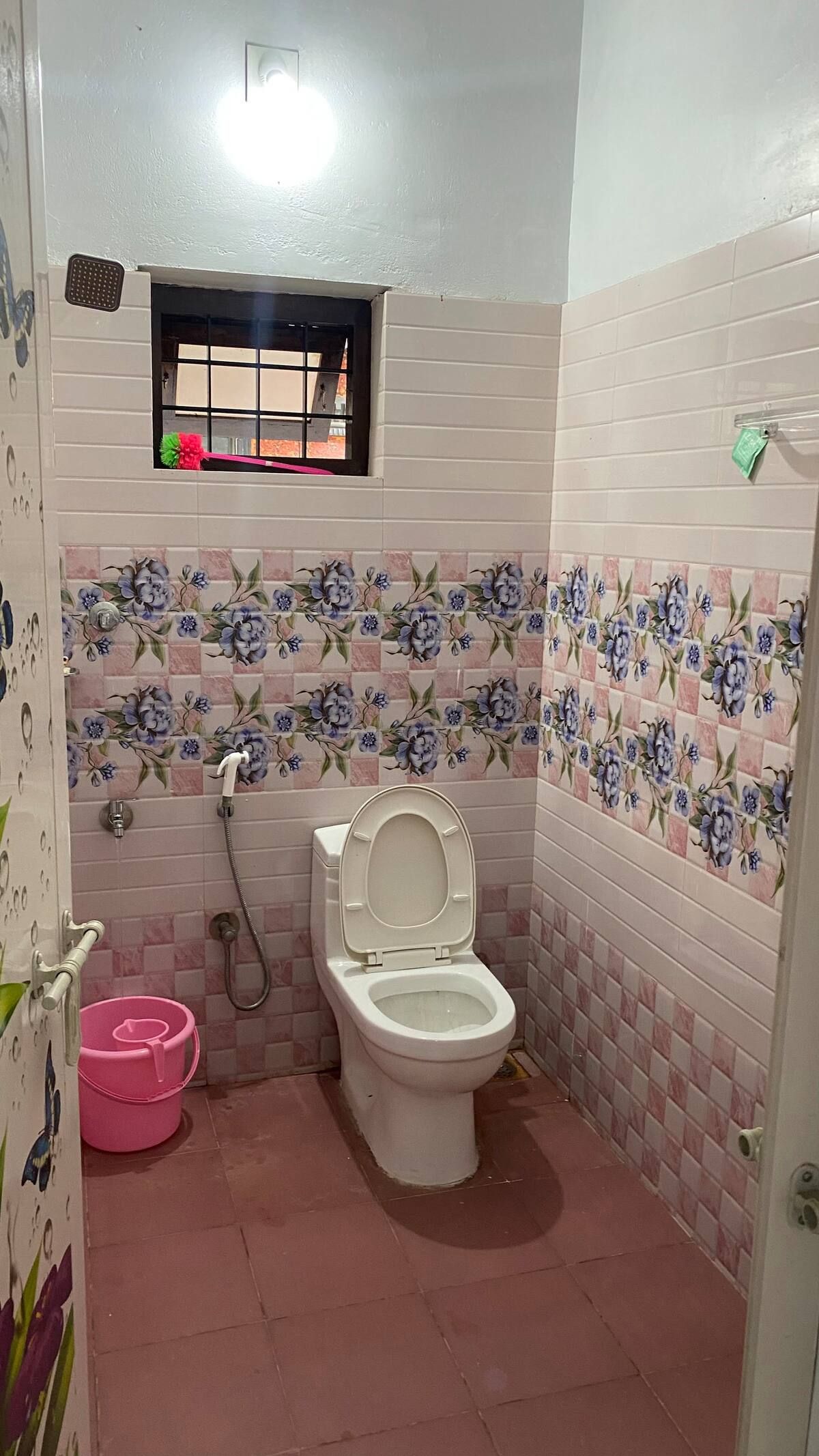 Bathroom with pink floral wall tiles and toilet.
